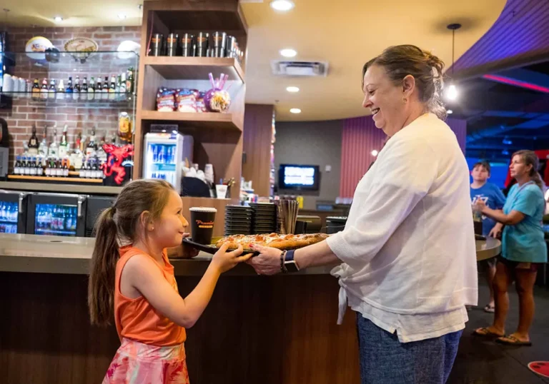 woman and young child enjoying pizza at Premier lanes